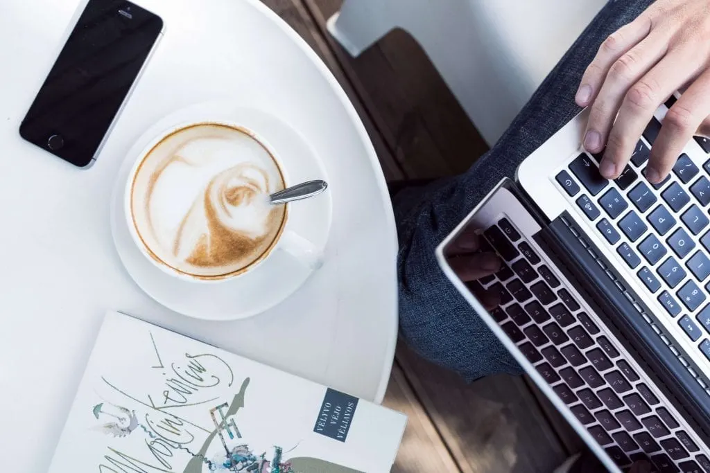 person using laptop near cup of coffee, www.everythingabode.com