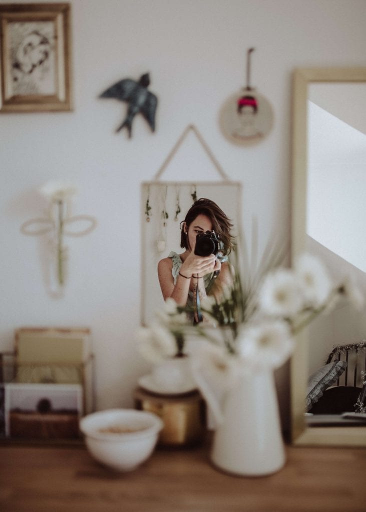 woman holding DSLR camera taking photo in front mirror inside room, www.everythingabode.com