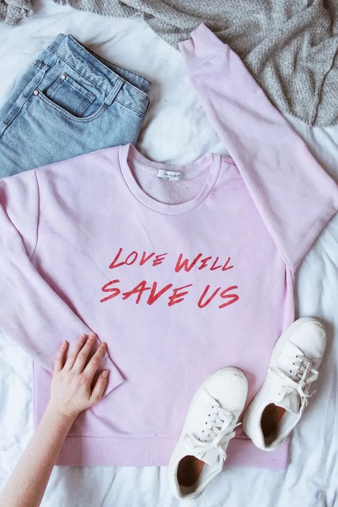 Pick out your outfit the night before tip - pink sweater with jeans and white runners with girls hand on sweater, sweater reads 'love will save us all' www.everythingabode.com