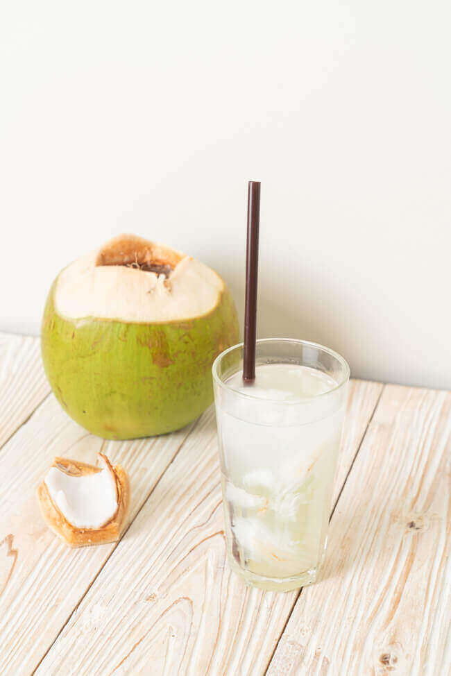 Coconut Water with a glass of coconut water with black straw for sickness and nausea relief