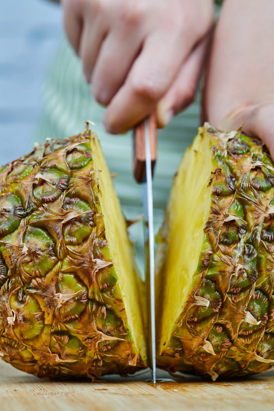 pineapple getting cut in half with sharp knife