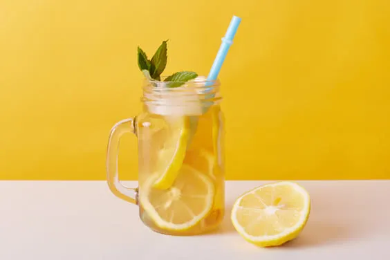lemon water in glass with lemons with straw for detoxing