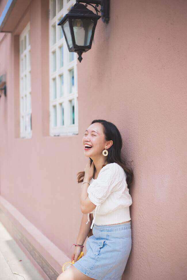 jitters and how to calm the jitters down - woman leaning up against wall smiling while calming her jitters down