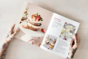 indoor hobby baking, woman holding onto cook book of inspiring pastries to make