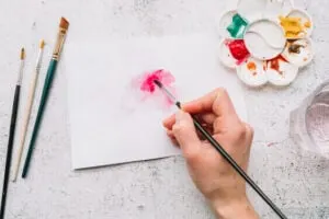 women painting water color flower in pink color on her day off