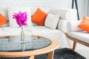 beautiful living room with white sofa and bright orange pillows as redecorating for a winter hobby is very popular