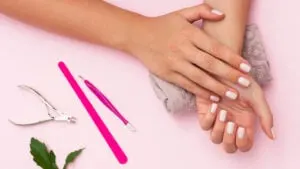 a pair of women's hands showcasing her new gel nails with soft white nail polish as a fun popular indoor hobby for women