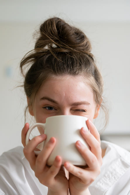 girl drinking coffee from coffee mug and winking to help boost dopamine