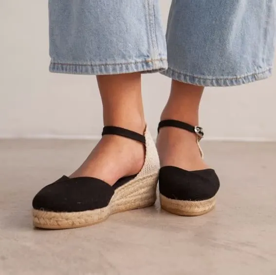 Black canvas espadrilles with jute soles paired with relaxed jeans.