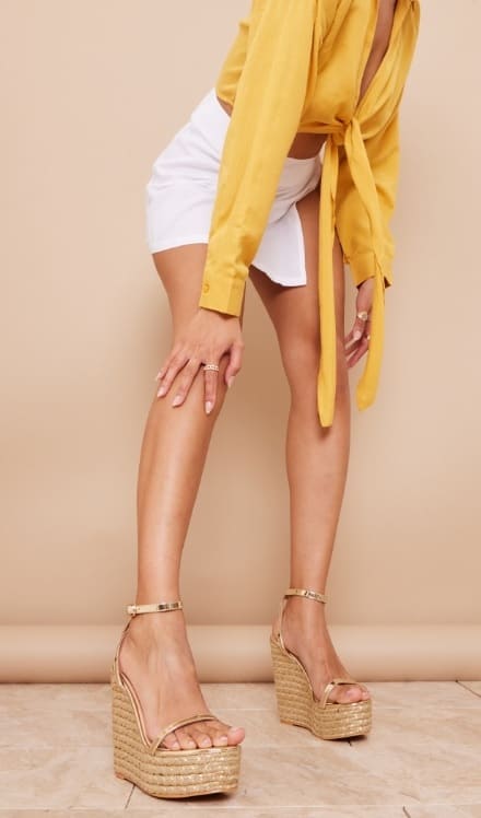 Woven espadrille wedges in a golden hue, perfect for adding a touch of glamour to any summer outfit.