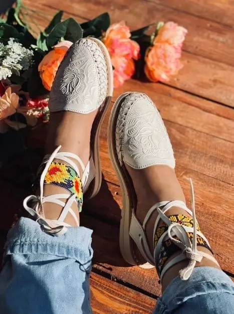 Vibrant beaded espadrille sandals with intricate designs on a sunlit wooden floor