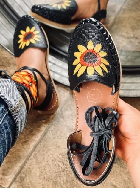 Black espadrille sandals with sunflower embroidery reflecting in a mirror