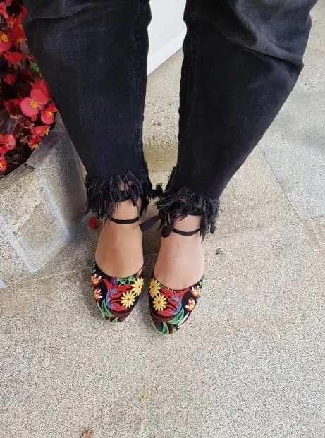 Colorful floral embroidered espadrille flats with ankle ties, paired with frayed black jeans