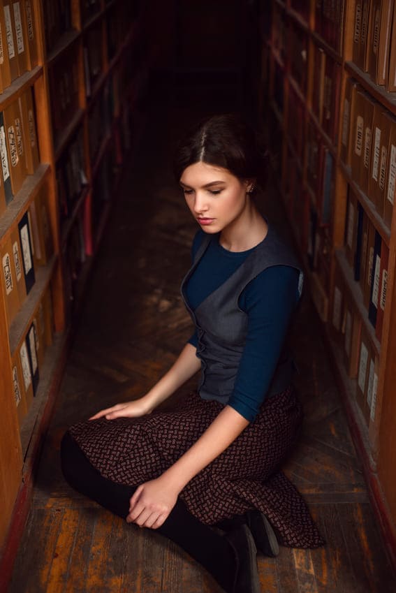 a woman wearing a dark academia outfit in a library