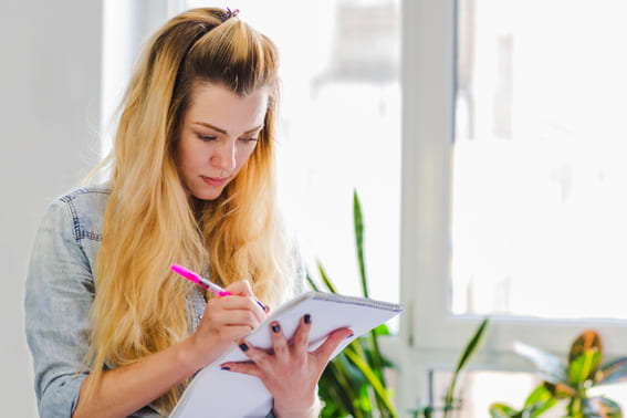 woman very focused looking at her journal prompts holding a pink pin