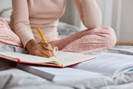 woman in her pink pajamas writing in her journal