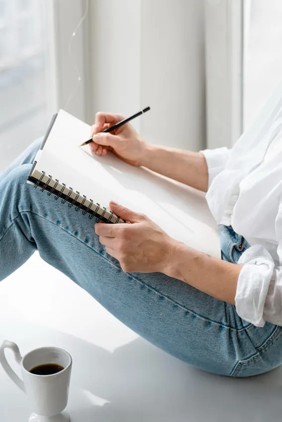 woman sitting with a clear page in her notepad to journal her journal prompts for the day