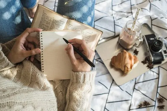 woman journaling with pastry and tea