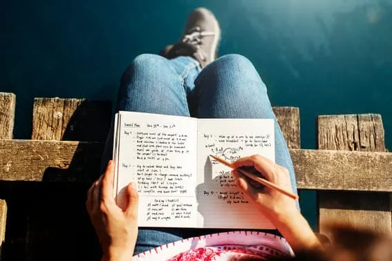 a woman sitting and reading her goals and aspirations in her journal