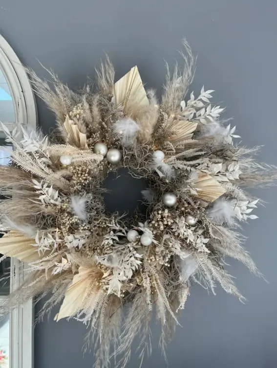 Neutral-toned bohemian wreath with feathers and baubles.