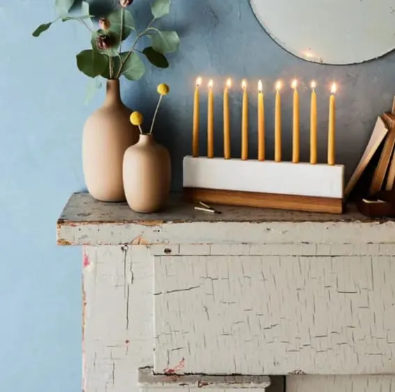 A modern menorah display for Hanukkah on a vintage sideboard.