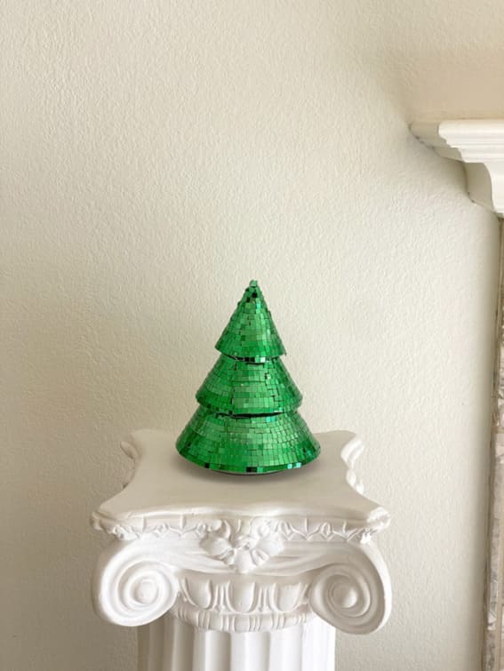 A green mosaic glass Christmas tree on a classical pedestal.