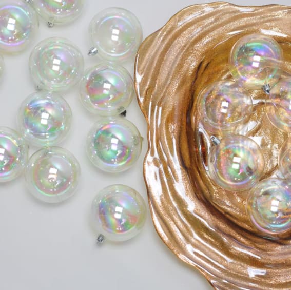 Clear iridescent Christmas baubles beside a gilded decorative piece.