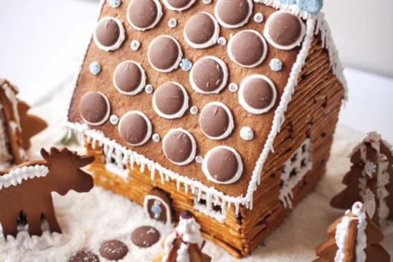 A gingerbread house with chocolate button shingles and pretzel log details.