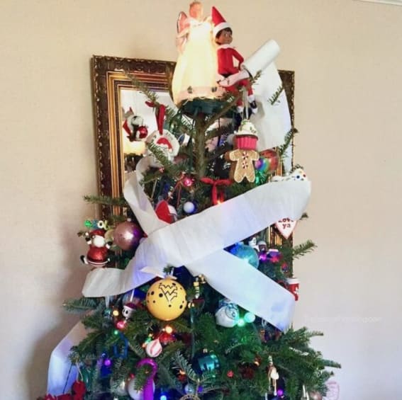 Elf on the Shelf gets creative with tree decor using toilet paper.
