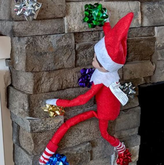 Elf on a festive climbing adventure up a fireplace.