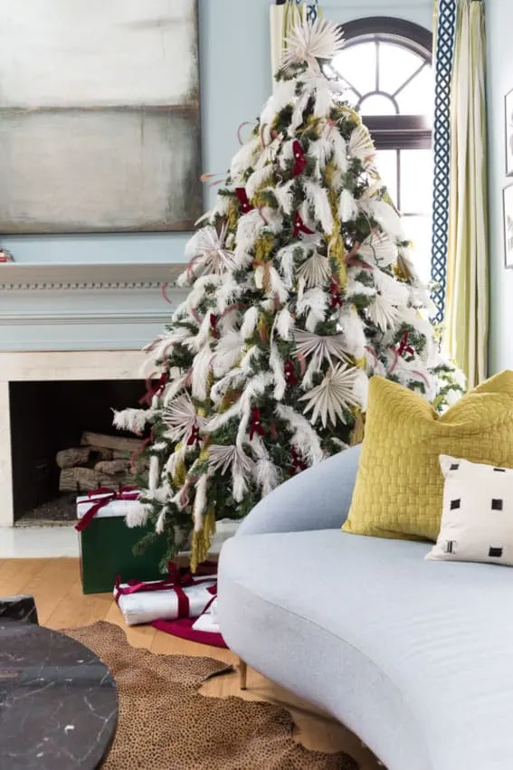 Green Christmas tree heavily adorned with white feathers.