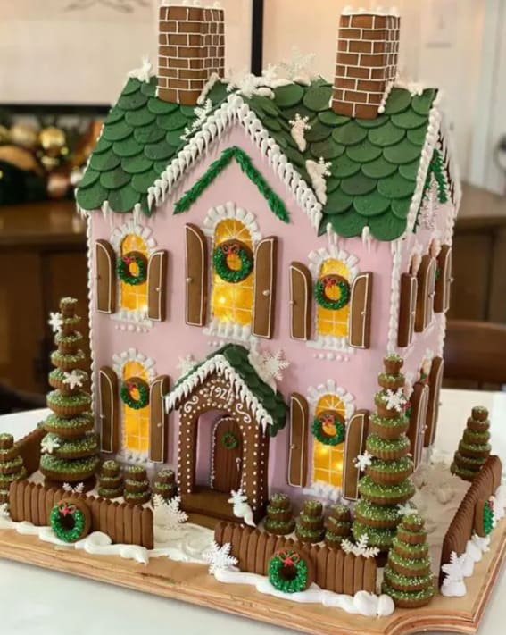 A lavishly decorated two-story gingerbread house with stained glass candy windows and snowflake accents.