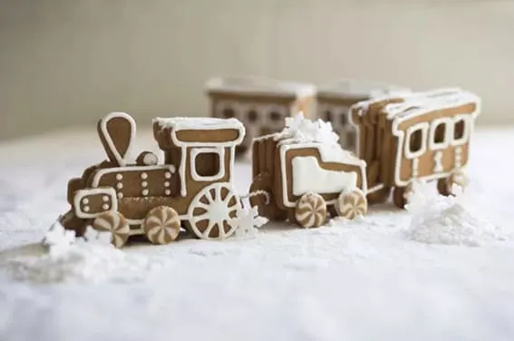 A gingerbread train with frosty icing accents chugs through a snowy scene.