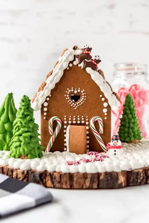 A classic gingerbread house with candy cane details and a snowy icing base.