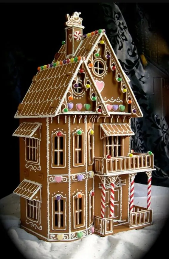 A multi-story gingerbread house with ornate icing details and colorful candy accents.
