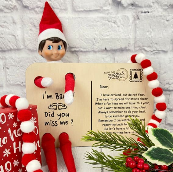 Elf on the Shelf posing with a welcoming postcard.
