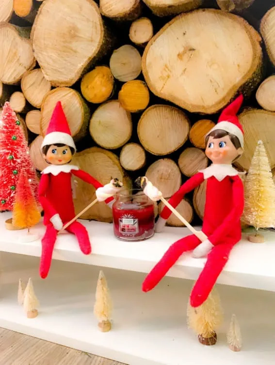 Two elves are roasting marshmallows over a candle.
