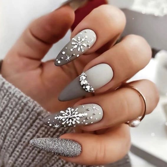 Festive almond nails with snowflake designs and glitter accents.