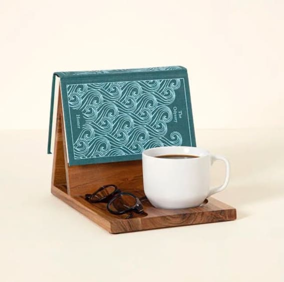 A stylish teakwood desk stand holding a book next to a coffee cup.