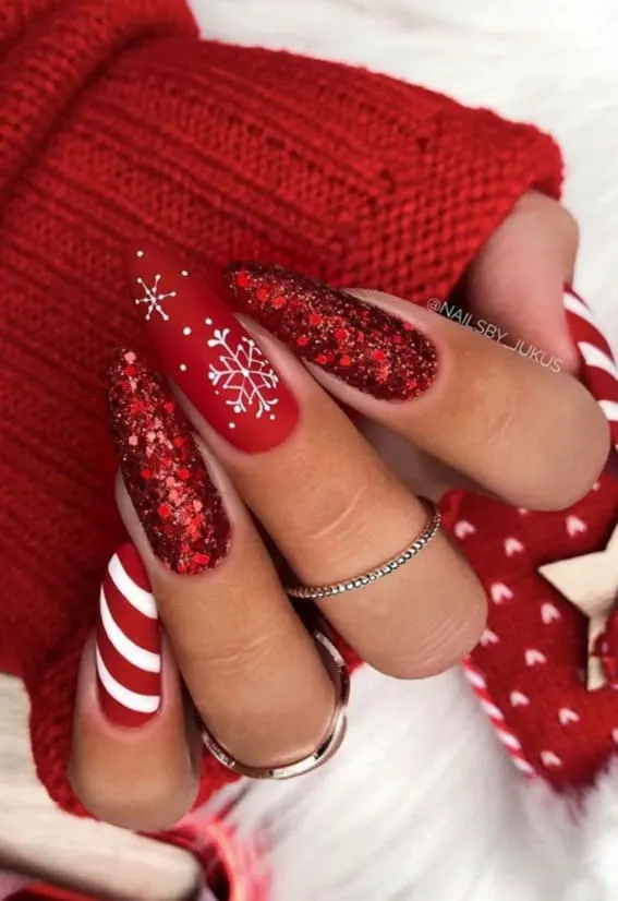 Festive red nails with glitter, snowflake, and candy cane stripe designs.