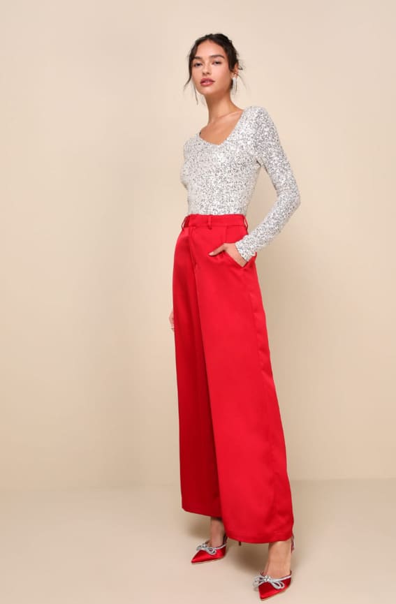 Outfit featuring a sparkling silver sequin top with elegant long sleeves, complemented by vibrant red wide-leg trousers and matching heels.