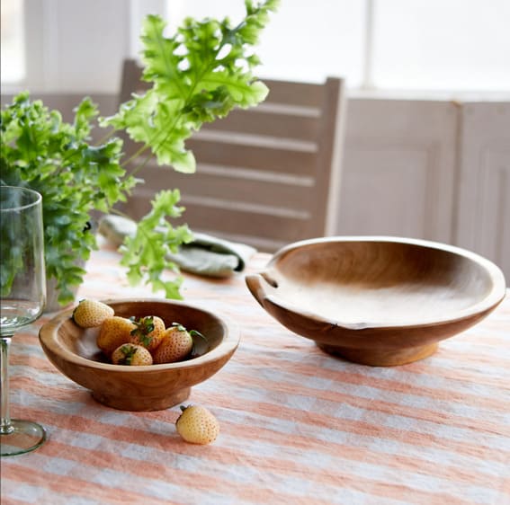 A rustic-footed teak root serving bowl on a table.