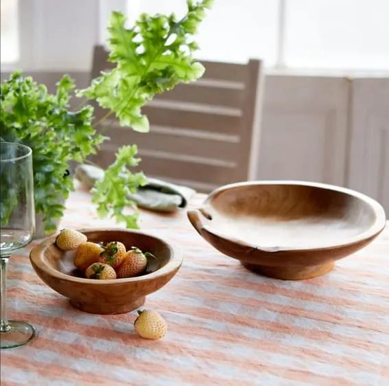 A rustic-footed teak root serving bowl on a table.