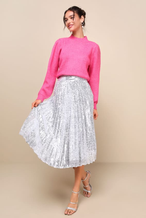 Outfit featuring a cozy pink knit sweater tucked into a shimmering silver sequin skirt for a playful yet warm holiday look.