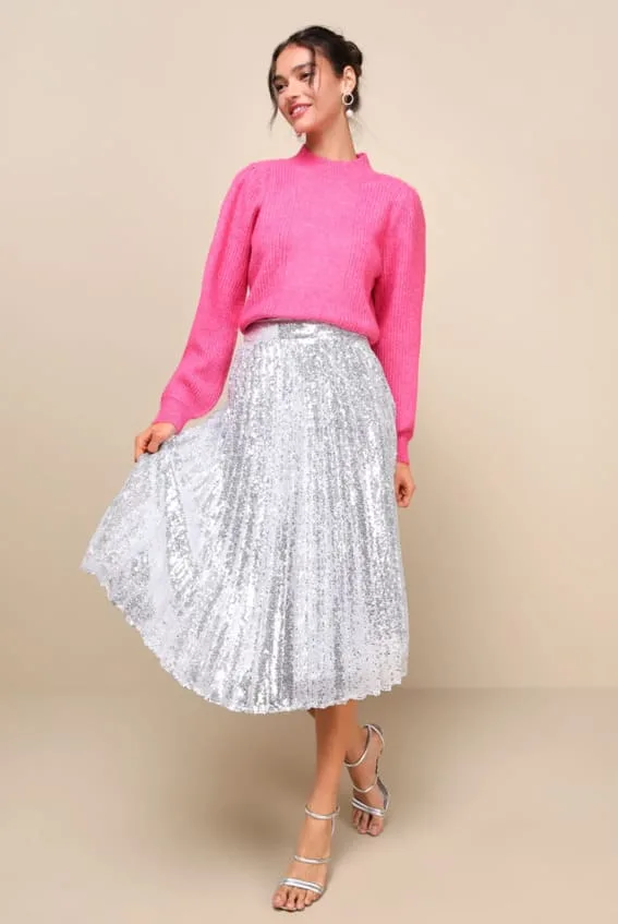 Outfit featuring a cozy pink knit sweater tucked into a shimmering silver sequin skirt for a playful yet warm holiday look.