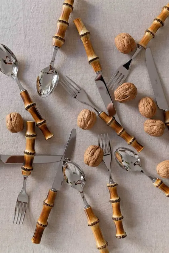  A 12-piece bamboo cutlery set arranged artistically among walnuts.