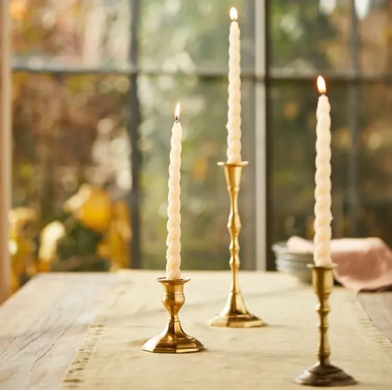 Three twisty taper candles on brass candle holders.