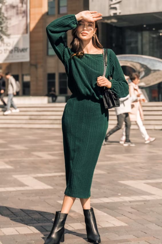 Model in a ribbed forest green dress with ankle boots.
