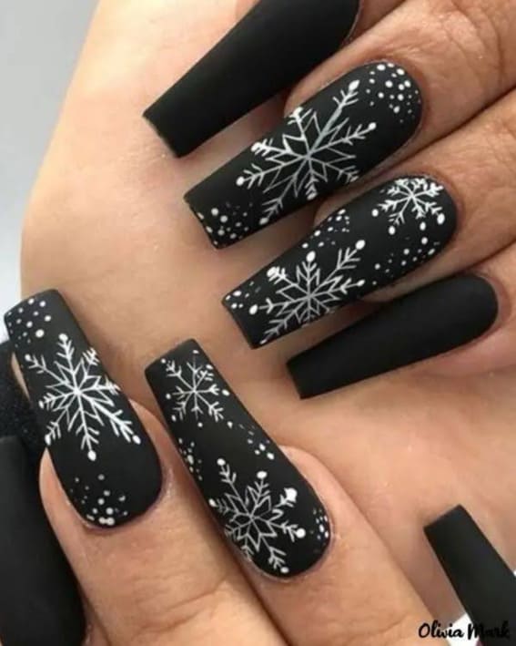 A picture showing off shiny black nails, each with a different snowflake drawn in white.