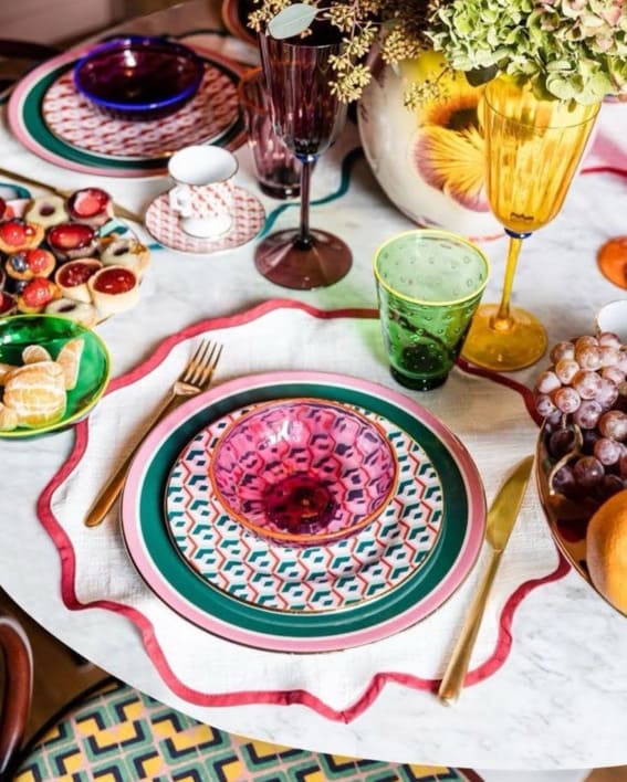 Colorful table setting with patterned plates and vibrant glassware.